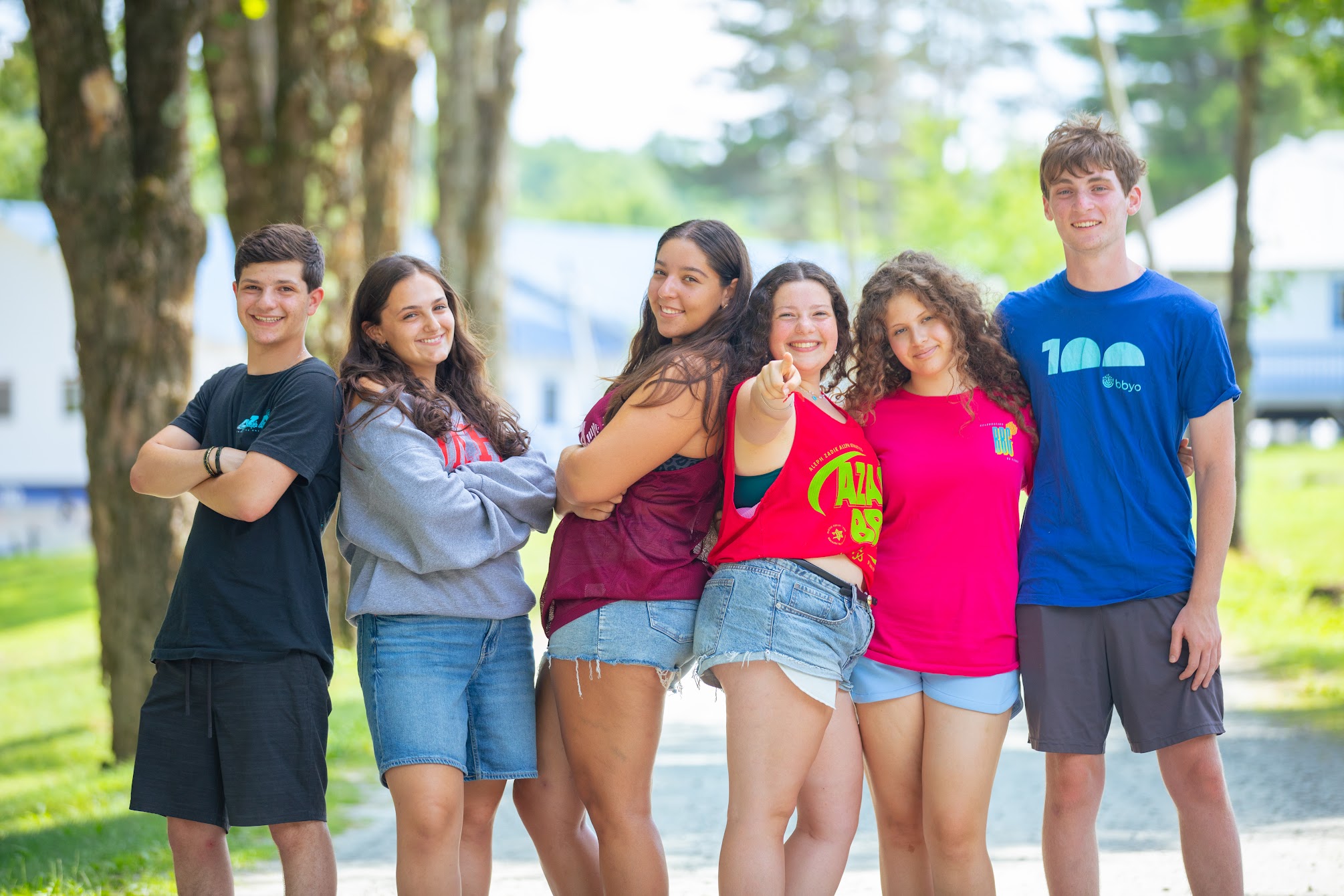 Un groupe hétéroclite de jeunes adultes sautant de joie dans un jardin verdoyant lors d'un événement communautaire.